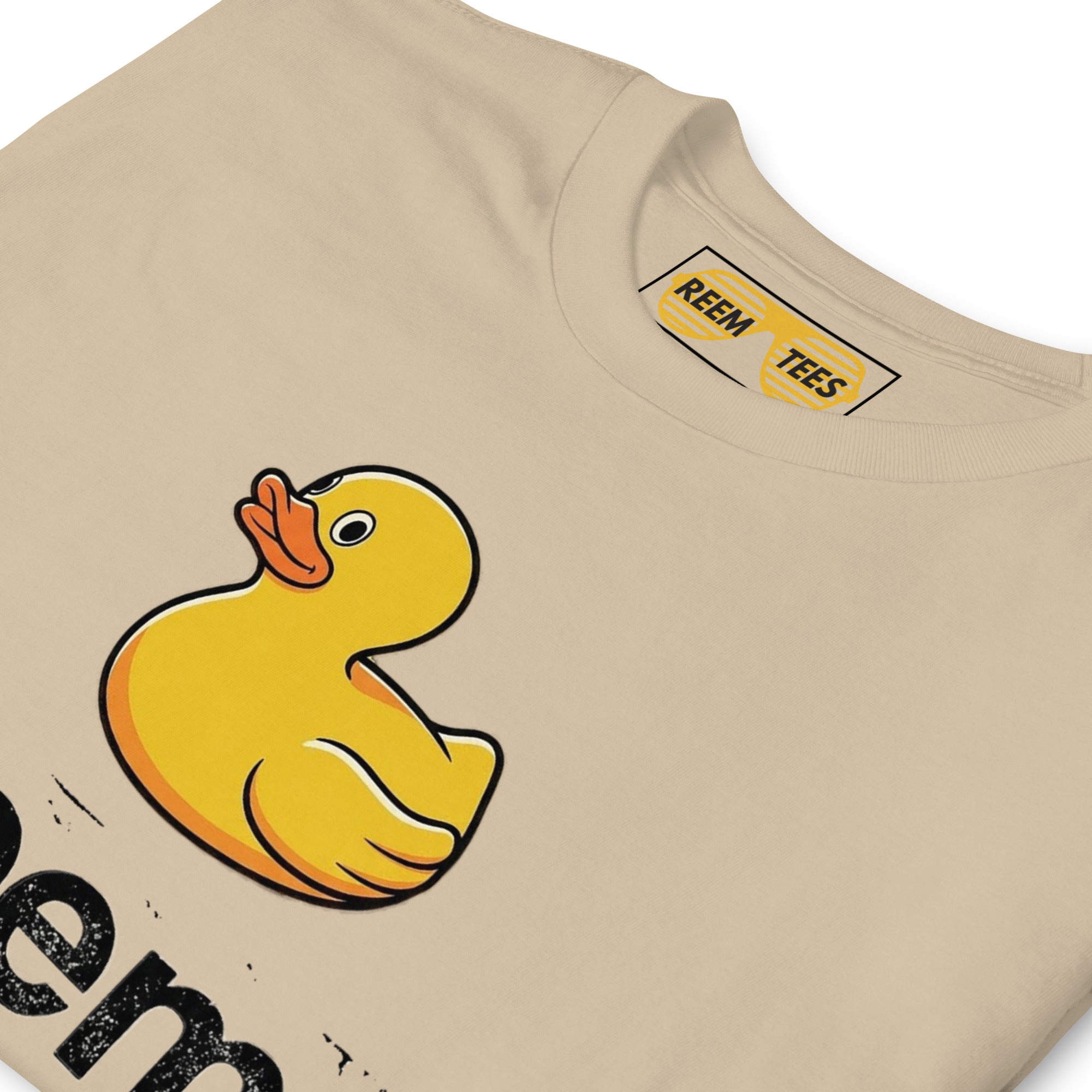 Unisex CLASSIC tee by Reem Tees featuring a dark Ducks Are Reem logo on a soft sand-colored fabric.